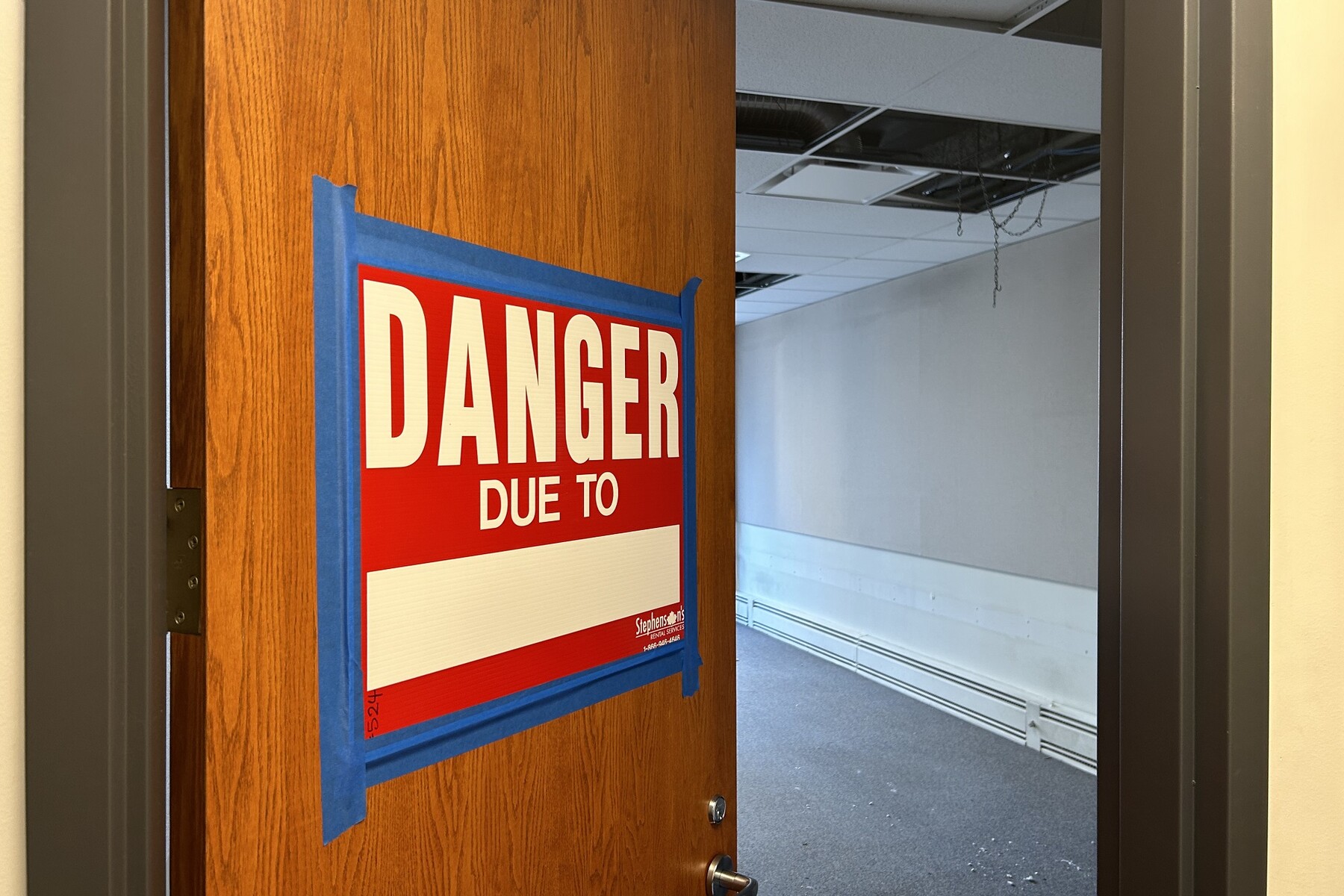 image of DANGER sign on door that is slightly open to room of construction