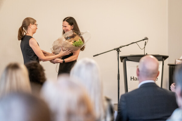 Barbara Gibson giving flowers to Brenda Mori